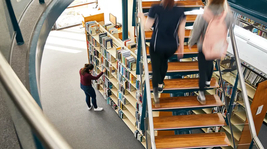 Photo of two people walking up stairs in a library.