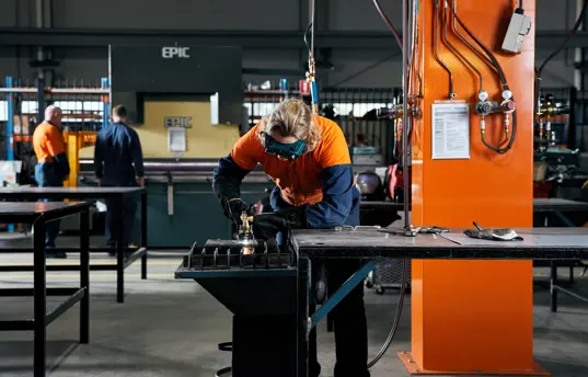 Photo of a tradesperson working on a machine in a workshop.