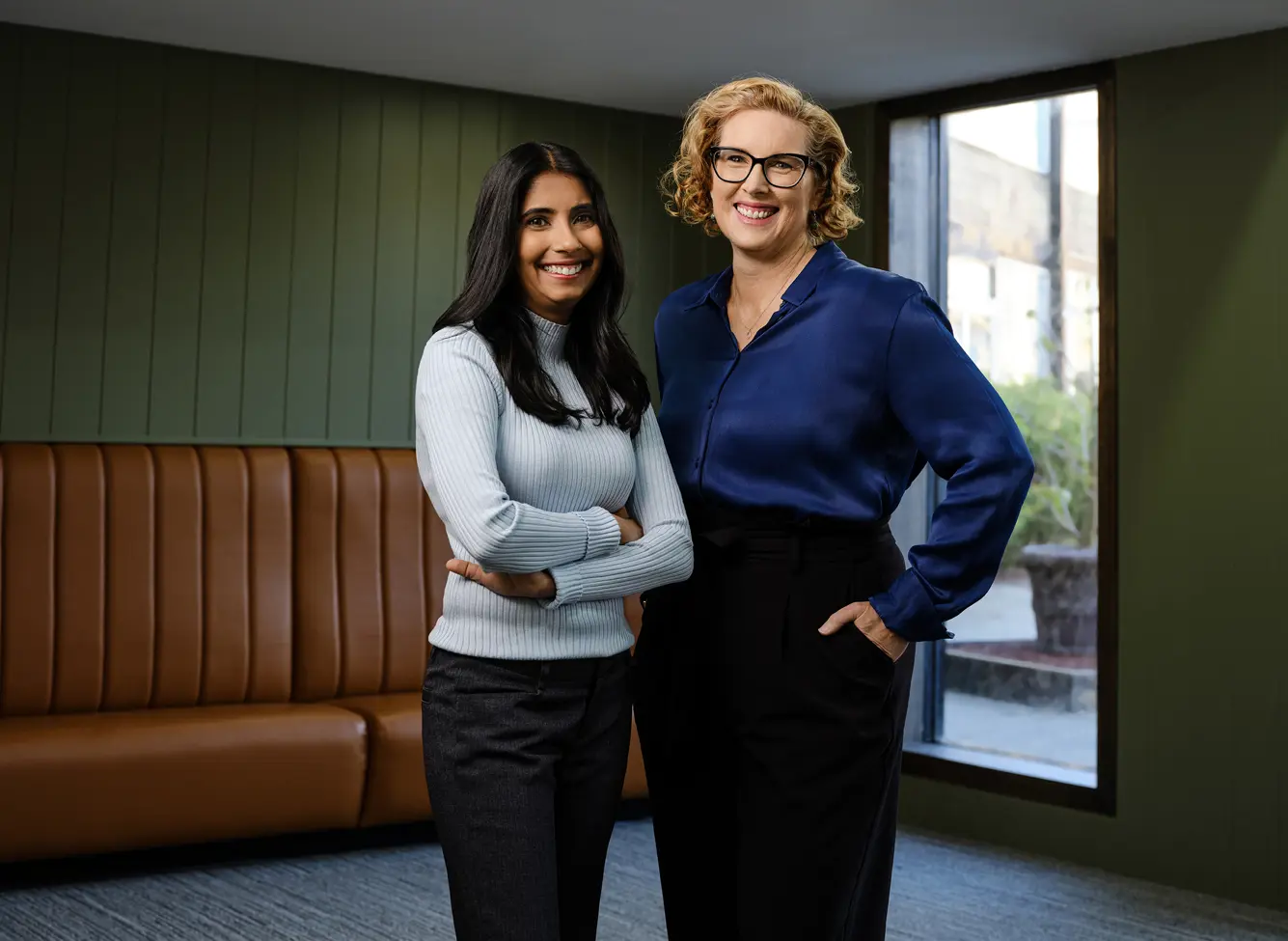 Photo of two people standing in front of a small window in a vintage looking room.