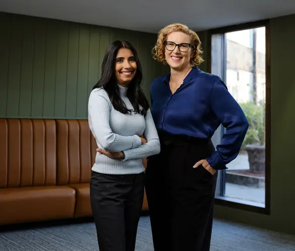 Photo of two people standing in front of a small window in a vintage looking room.