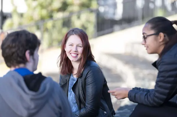 Photo of three happy people sitting outside.
