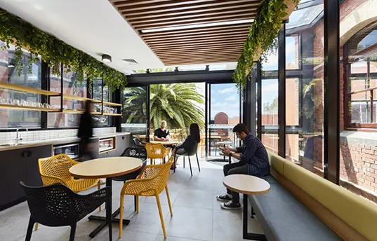 Students in a modern eating area with architectural features and greenery