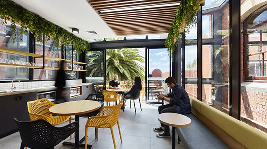 Students in a modern eating area with architectural features and greenery