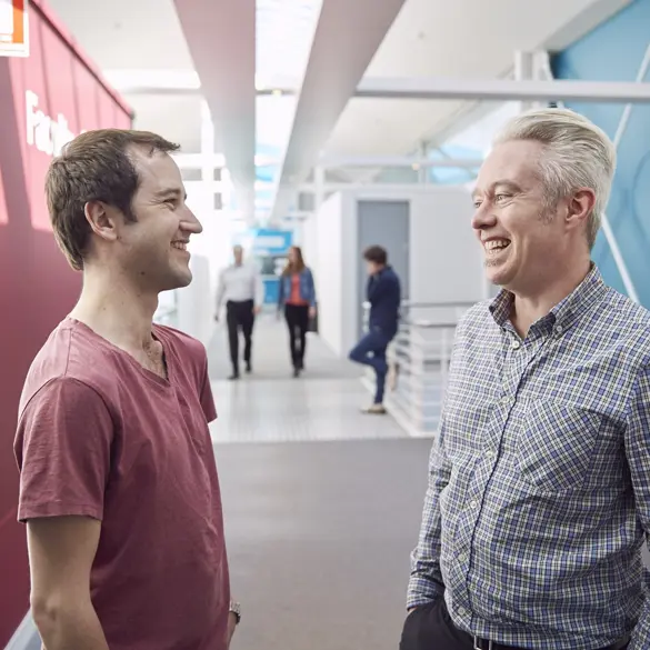 Photo of two people talking in a modern hallway