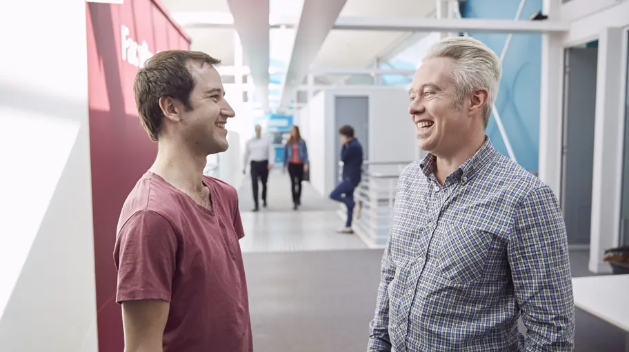 Photo of two people talking in a modern hallway
