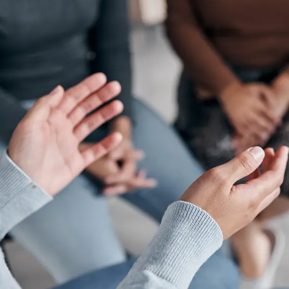 Photo of a pair of hands, in the background there are blurred legs